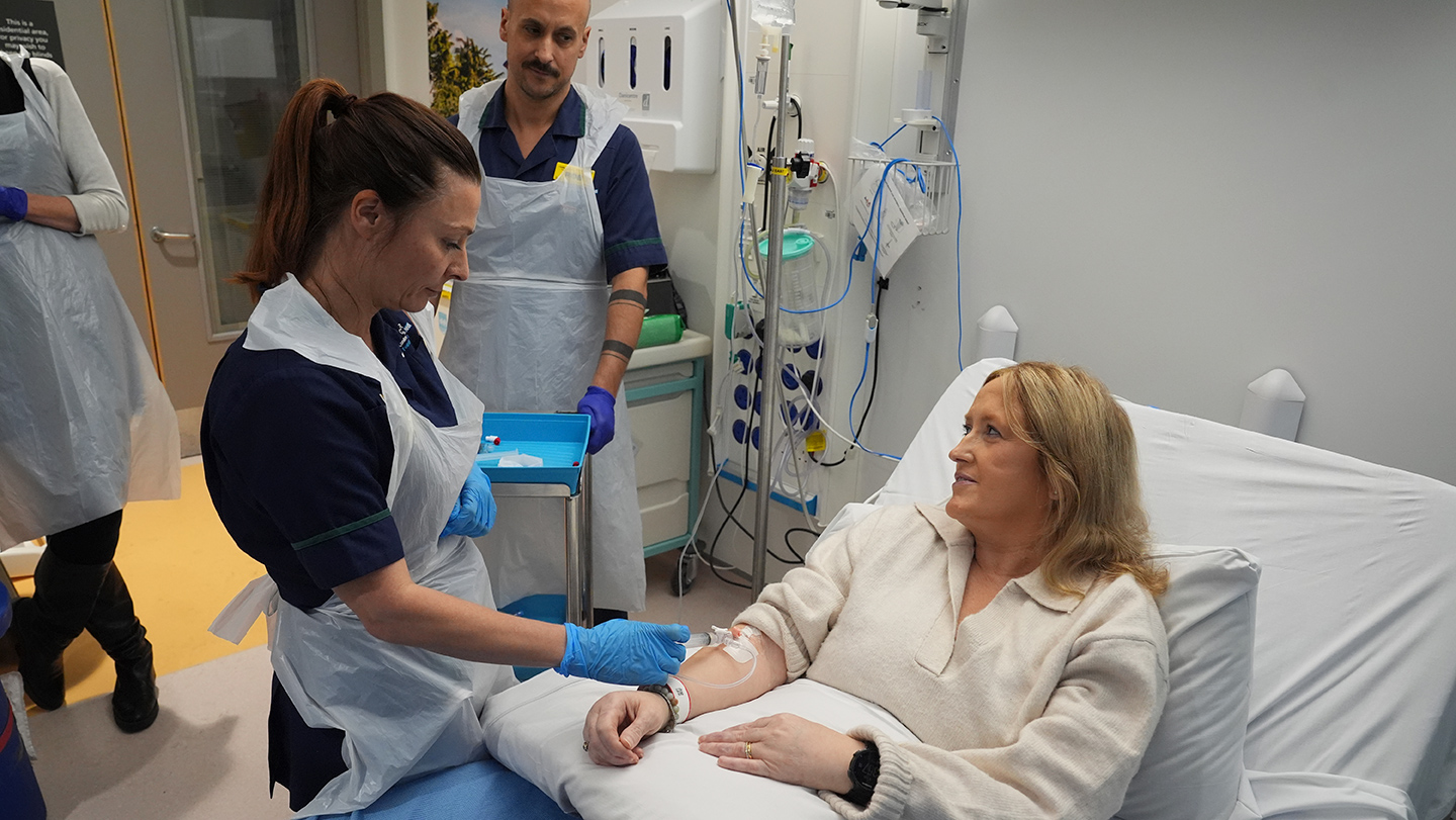 Paciente recibe una infusión intravenosa en una cama de hospital durante un tratamiento.