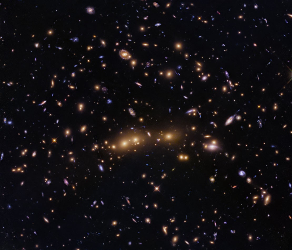 Vista del cúmulo CL0016+1609, con grandes galaxias elípticas en el centro y arcos de lente gravitacional alrededor.