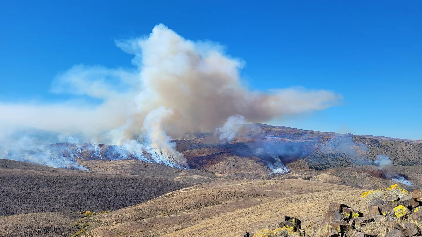 Humo y llamas de un incendio controlado sobre una ladera seca en Idaho.