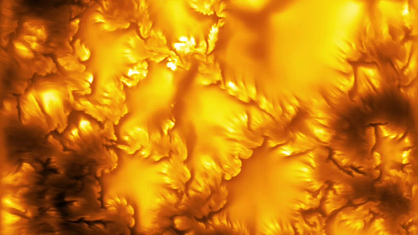 Imagen de alta resolución de la superficie del Sol con remolinos anaranjados de plasma magnetizado.