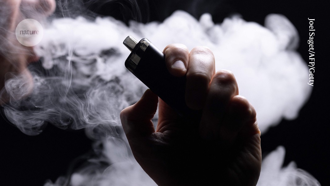 Persona sostiene un cigarrillo electrónico junto a una nube de vapor